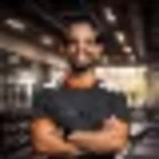 Foto de Lucas Lima, personal trainer, de braços cruzados dentro de um ginásio